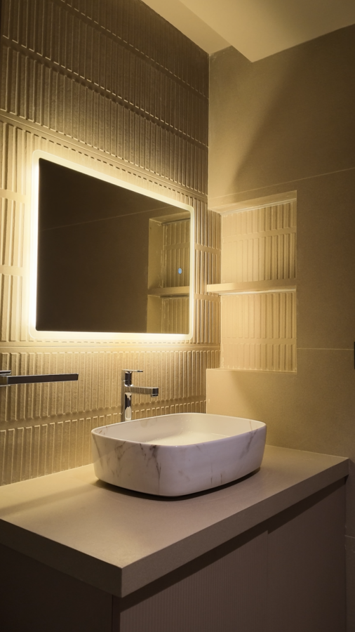 Video of a softly lit bathroom vanity with a rectangular LED mirror and textured tiles